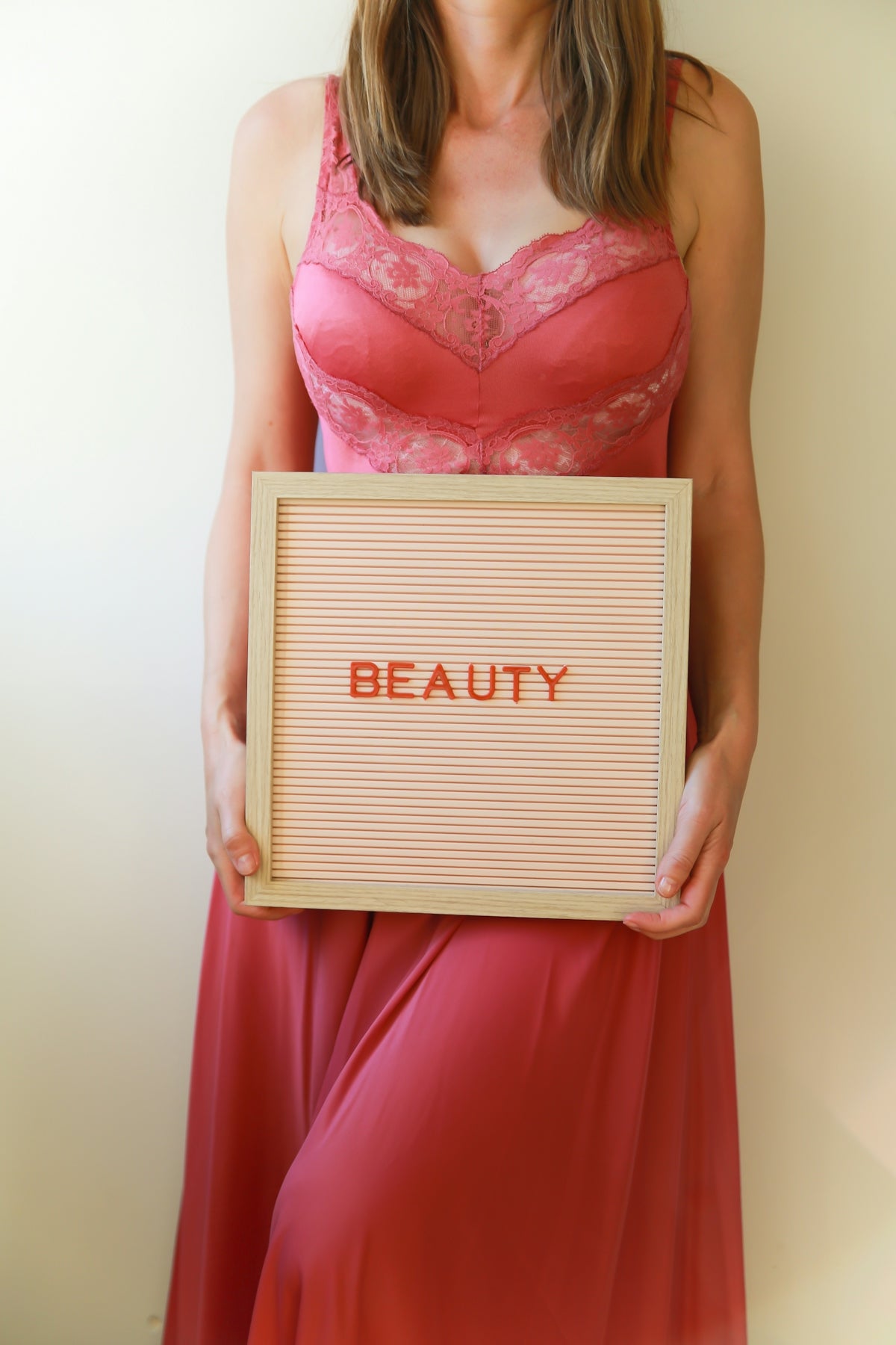 A woman in pink holds a sign that says beauty.