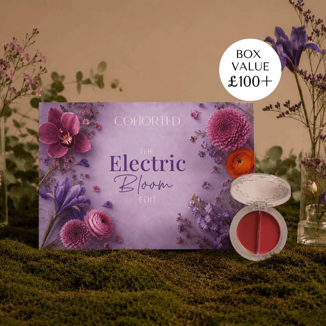 A floral makeup gift box labeled 'COHORTED The Electric Bloom Edit' sits on moss with flowers and a small open makeup compact beside it. A white circle badge reads 'BOX VALUE £100+'. KVD Beauty, sneak peek, subscription beauty box