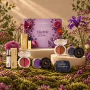Cohorted The Electric Bloom Edit beauty box displayed on a cream pedestal, surrounded by purple and pink flowers in a botanical setting, beauty boxes, UK, Gift